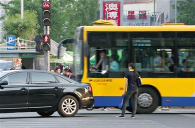 5月9日，朝阳路，一位闯红灯的市民被穿过路口的汽车“截停”在斑马线上。新京报记者 薛珺 摄